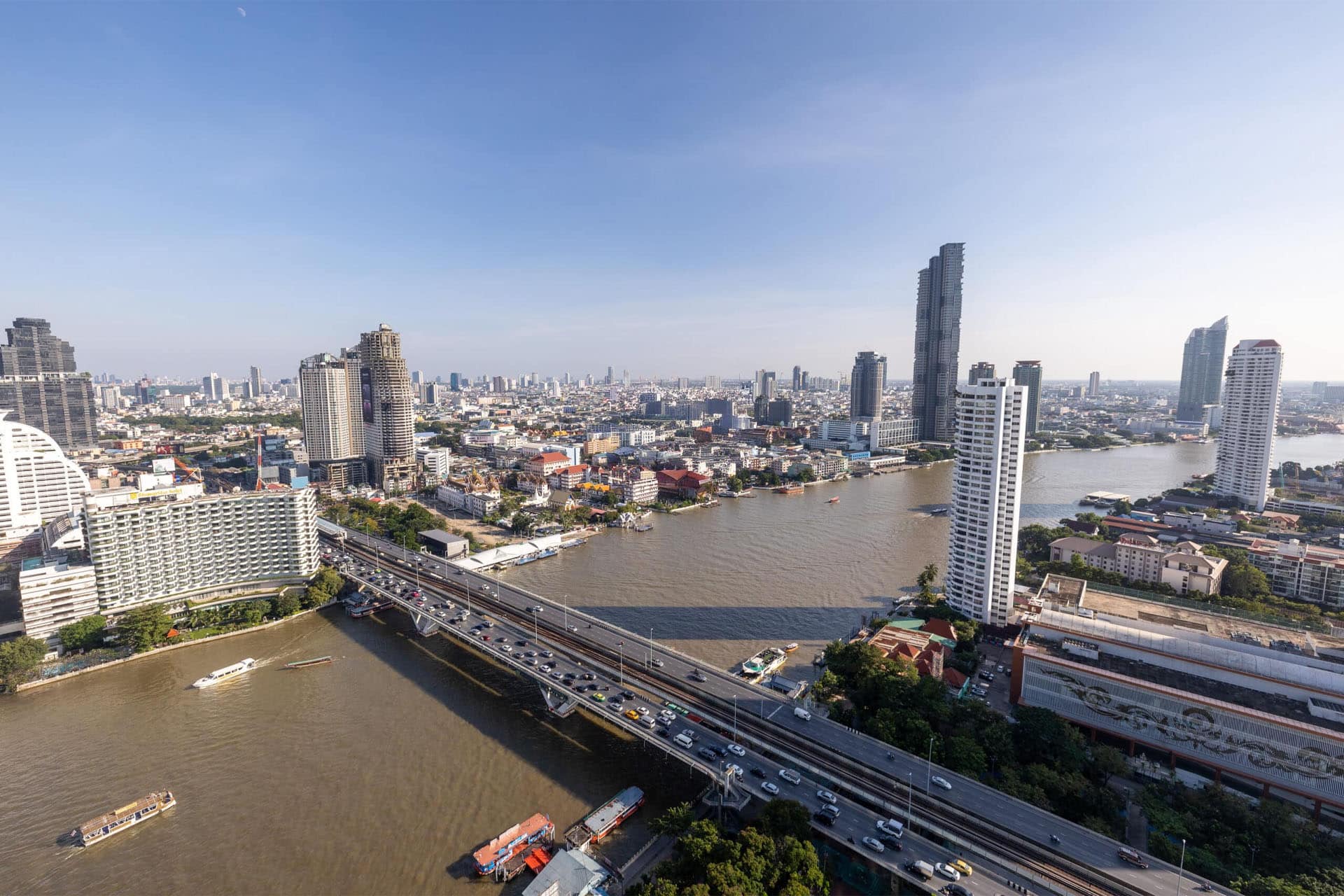 High-rise condominiums and office towers along the Chao Phraya River in Bangkok, showcasing prime waterfront real estate opportunities.